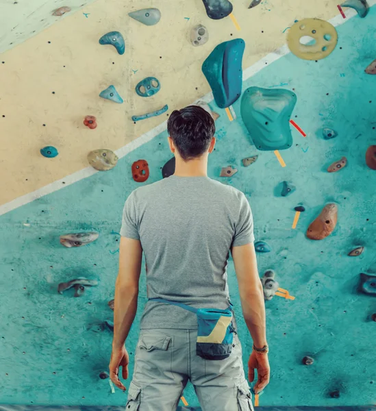 Man standing in front of a practical climbing wall — Stock Photo, Image