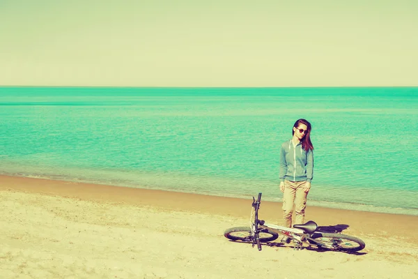 Dívka s kolo stojí na pláži — Stock fotografie