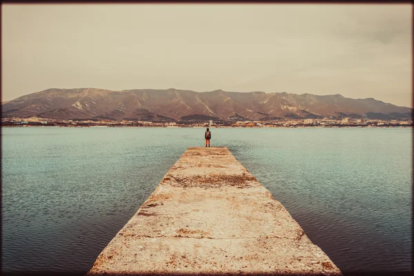 Caminante mujer de pie en el muelle frente a las montañas — Foto de Stock