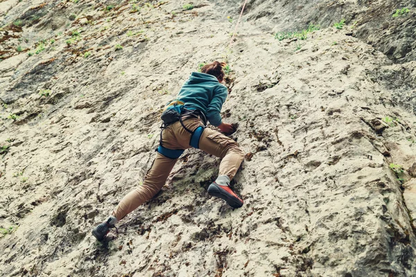 Активная молодая женщина карабкается по скале — стоковое фото