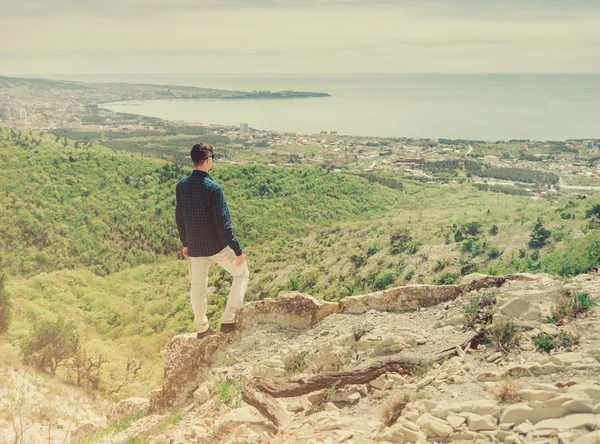 Hombre de pie en la cima de la montaña y mirando a la ciudad — Foto de Stock