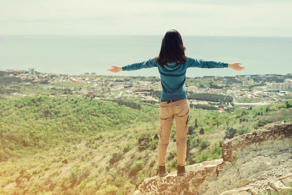 Traveler woman standing with raised arms on peak of rock — Stock Photo, Image
