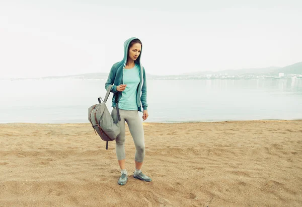 Woman with backpack standing on beach — Stock Photo, Image