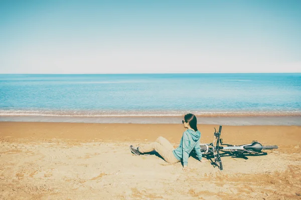 Žena odpočívá s kol na pláži — Stock fotografie