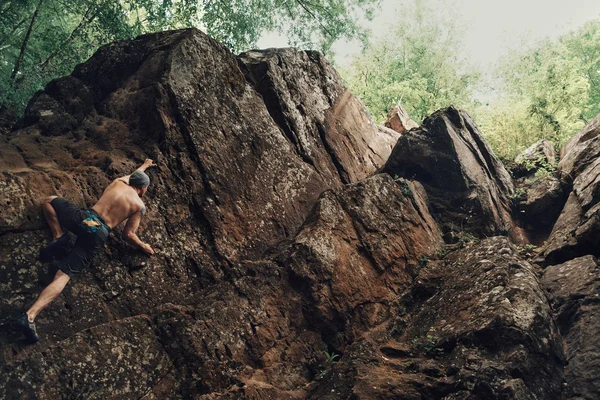 Sportlicher junger Mann klettert auf Steinfelsen — Stockfoto