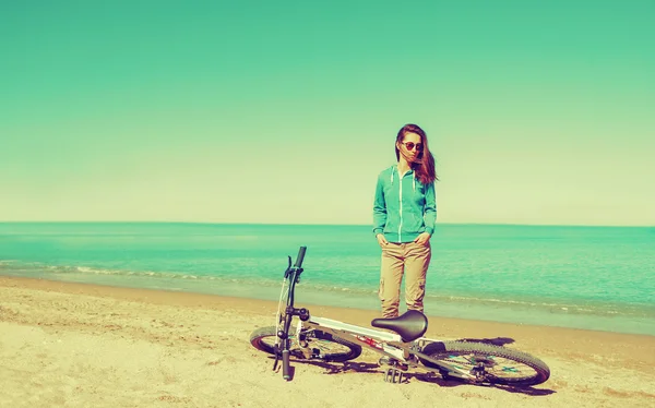 Žena s kolo stojí na pláži — Stock fotografie