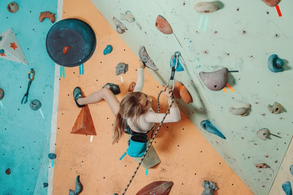 Chica escalando en rocas artificiales en el gimnasio — Foto de Stock