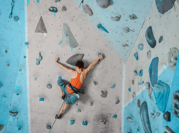 Boy in safety equipment climbing in gym — Zdjęcie stockowe