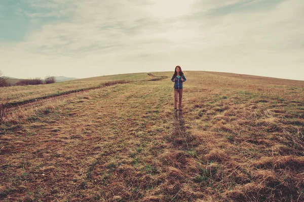 Femme avec sac à dos marchant sur prairie — Photo