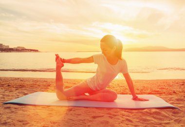 Kumsalda yoga yapan bir kadın.