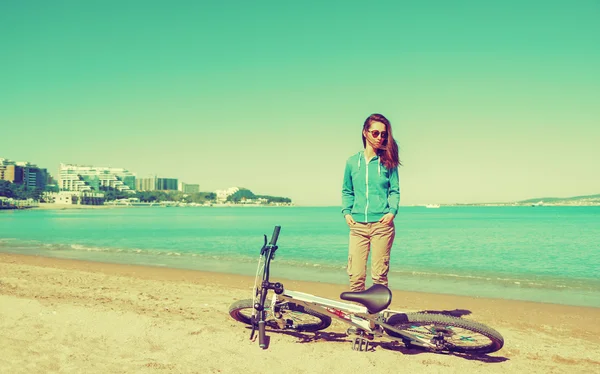 Женщина с велосипедом на песчаном пляже — стоковое фото