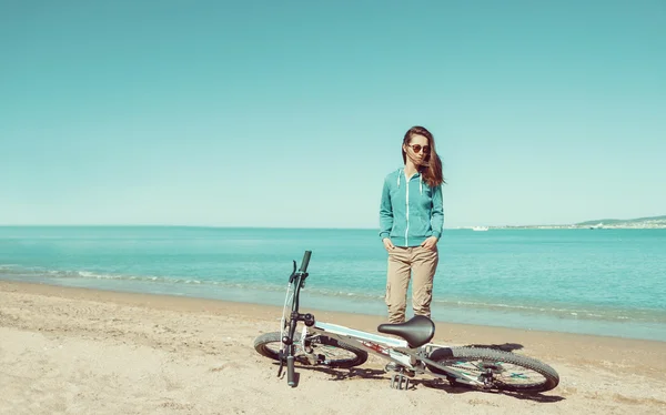 Женщина с велосипедом стоит на пляже — стоковое фото