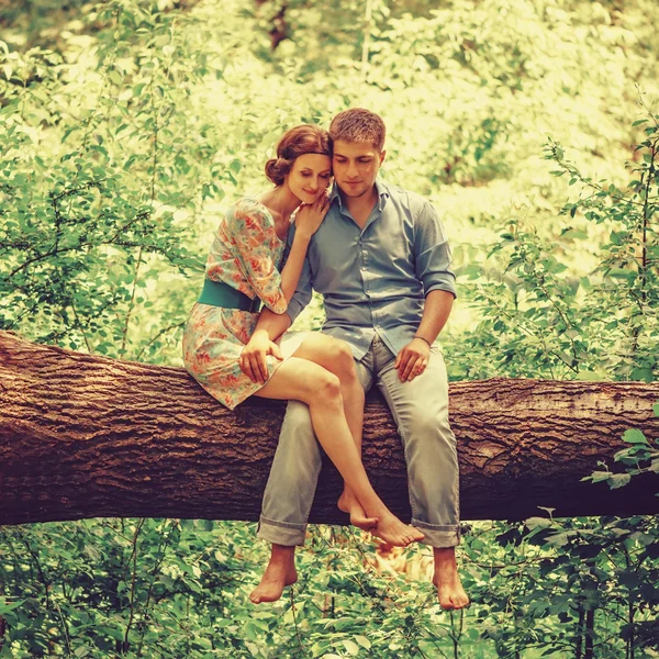 Улыбающаяся любящая пара сидит на дереве — стоковое фото