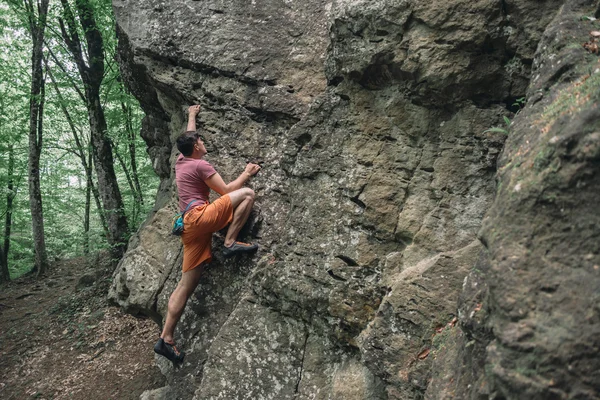 Homem começando a escalar na rocha de pedra — Fotografia de Stock