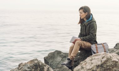 Gezgin kadın kıyısında oturan tablet ile 