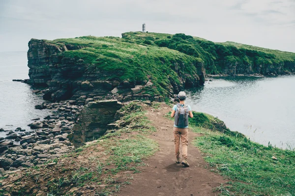 Γυναίκα με σακίδιο περπάτημα στο νησί στη θάλασσα — Φωτογραφία Αρχείου
