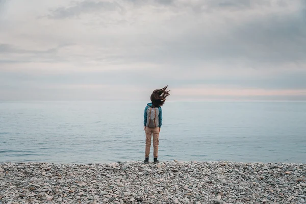 Mujer con mochila de pie en la costa — Foto de Stock