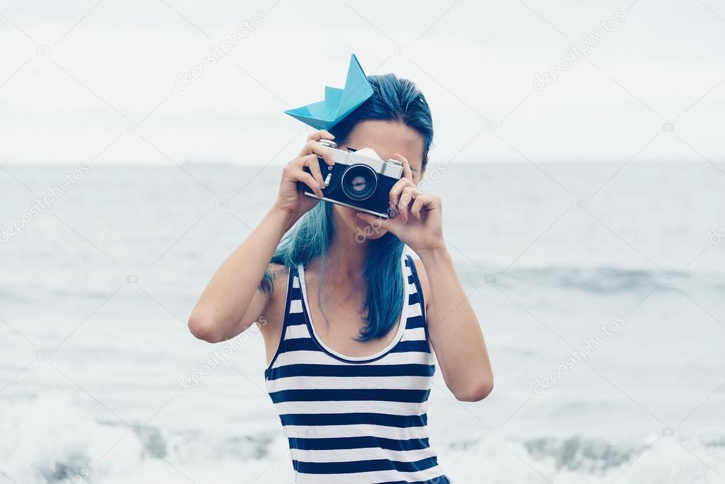 Beautiful girl takes a photograph on beach