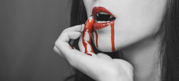 Женщина-вампир вытирает кровь с губ
