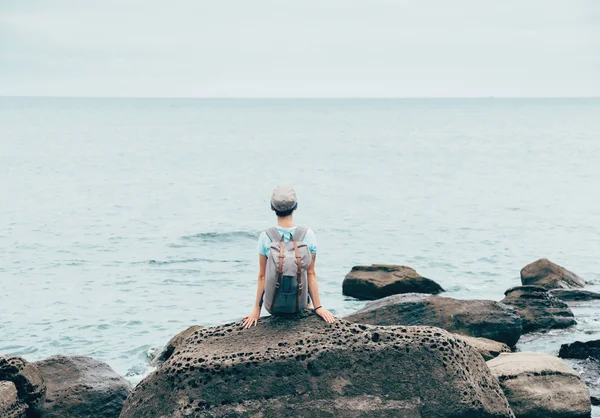 Traveler flicka vilar på sten kusten — Stockfoto