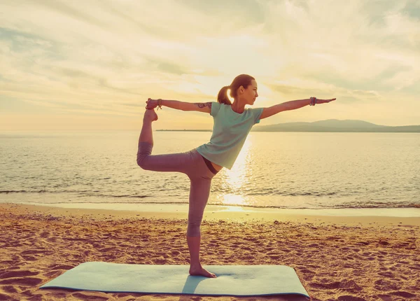 Junge Frau praktiziert Yoga am Strand — Stockfoto