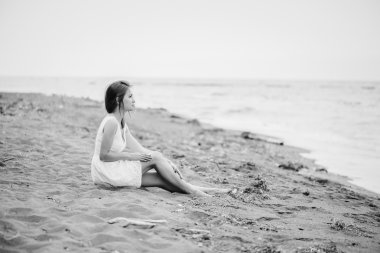 Kum plajı üzerinde oturan kız 