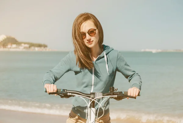 Девушка с велосипедом на пляже — стоковое фото
