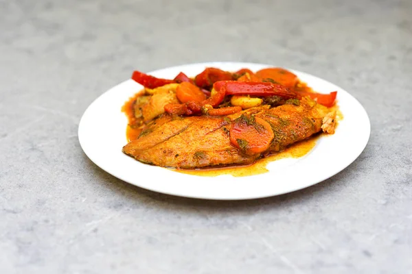 Fish in hot tomato sauce with vegetables on white plate. Home made tasty food ready to eat. — Stock Photo, Image