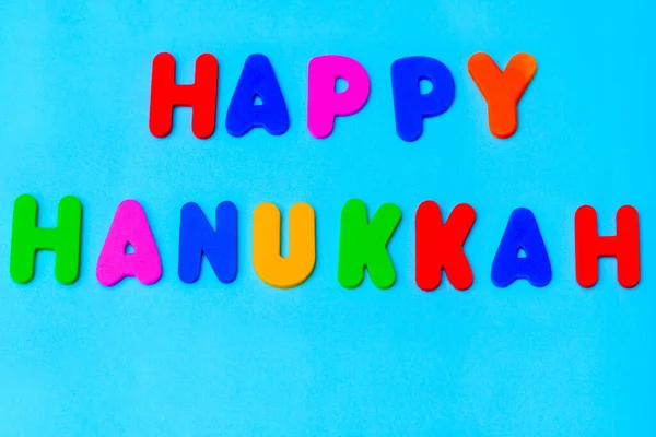 青い背景にハッピーハヌカカラフルなテキスト ユダヤ人の休日チャヌカグリーティングカード — ストック写真