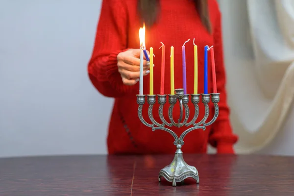 Joodse vrouw die Chanoeka Kaarsen aansteekt in een menorah. — Stockfoto