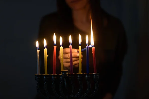 Joodse vrouw die Chanoeka Kaarsen aansteekt in een menorah. — Stockfoto