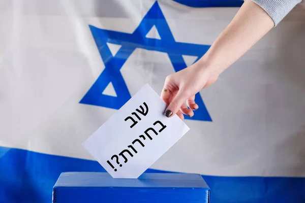 Mulher israelense vota em um posto de votação no dia da eleição. Feche a mão. Texto hebraico eleições novamente. — Fotografia de Stock