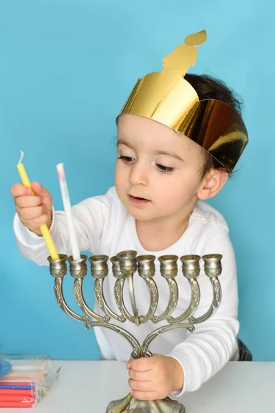 Little jewish boy puts candles on traditional menorah. — Stock Photo, Image