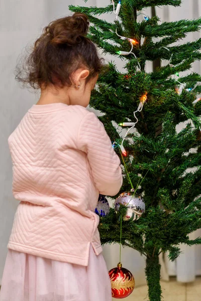 Очаровательный малыш украшает рождественскую елку стеклянными безделушками дома. — стоковое фото