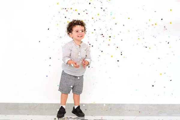 Cute baby boy enjoying a holiday and throwing confetti. — Stock Photo, Image