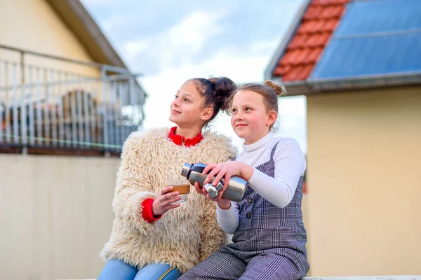 Smiling friends socializing, drinking tea from reusable cup and watching the sun go down in the evening on roof terrace. — Stock Photo, Image