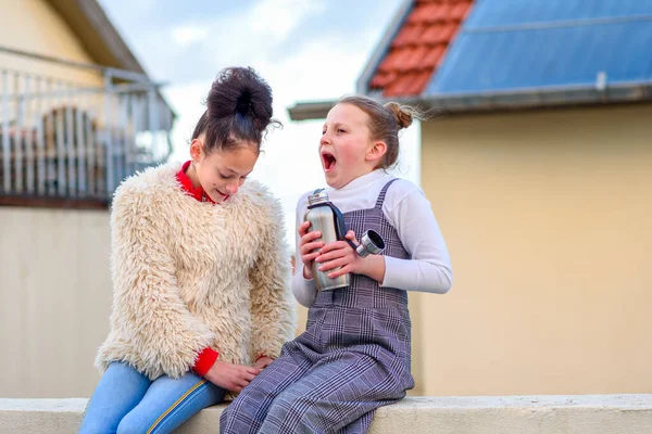 两个快乐的女孩在城外感到寒冷。屋顶上有可重复使用的瓶子和杯子的青少年. — 图库照片