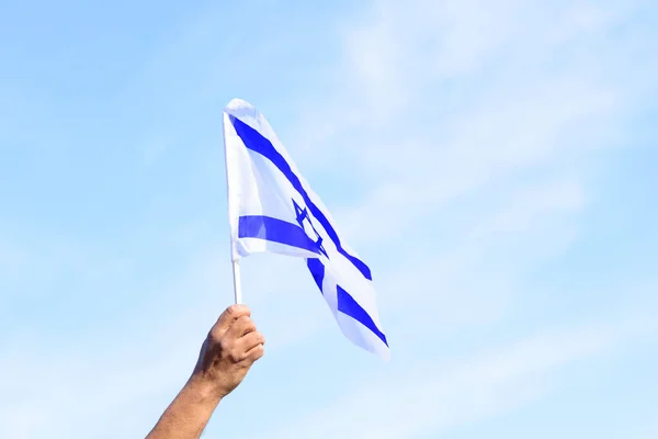 Drapeau israélien, main d'homme, ciel bleu. — Photo