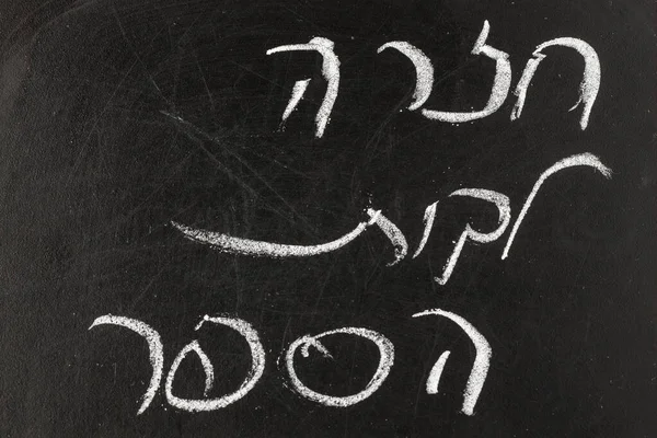 Chalkboard with Back to School in Hebrew written on the black board. Ліцензійні Стокові Фото