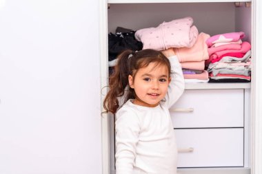 Güzel küçük kız giyecek kıyafet seçiyor..