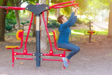 60-70 yaşlarındaki son sınıf öğrencisi kadın spor aletleriyle dışarıda spor yapıyor..