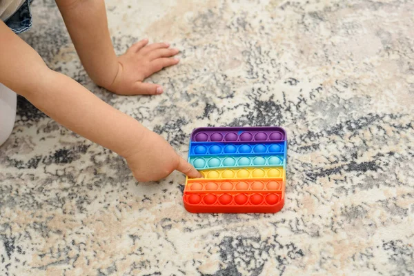 Kinderhände aus nächster Nähe, die mit dem bunten Pop-It-Fidget spielen. Crop smart kid spielt Spiel und findet Lösung. — Stockfoto