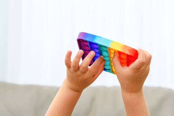 Kinderhände aus nächster Nähe, die mit dem bunten Pop-It-Fidget spielen. Crop smart kid spielt Spiel und findet Lösung. — Stockfoto