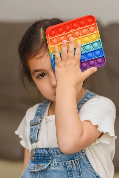 Schöne schwarze Haare Kind spielt mit flexiblen Spielzeug der Pop It zappeln. — Stockfoto