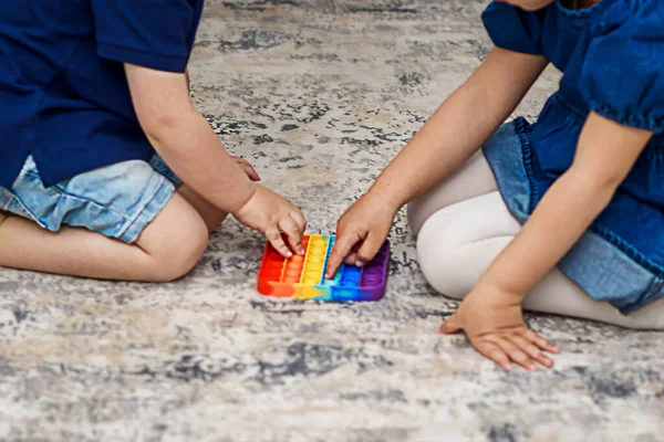 Zwei süße Kinder spielen mit flexiblem Spielzeug, dem Pop It Fidget. — Stockfoto