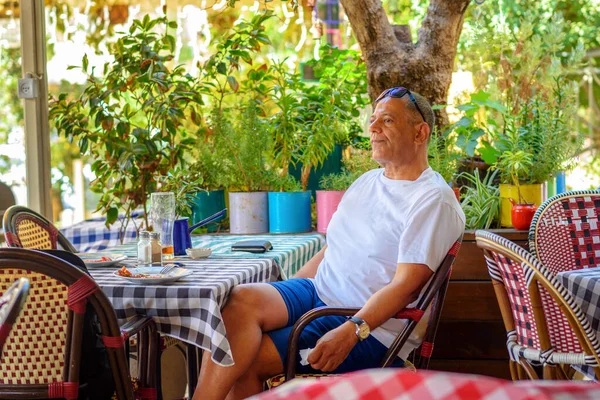 Вид збоку красивий чоловік середнього віку, що сидить на відкритій терасі ресторану . — стокове фото