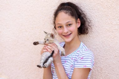 Mutlu çocuk kollarında bir kedi tutuyor. Kız küçük bir kedi yakaladı..