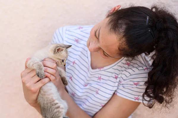 Un bambino felice tiene un gatto tra le braccia. Ragazza catturato un piccolo gattino. — Foto Stock