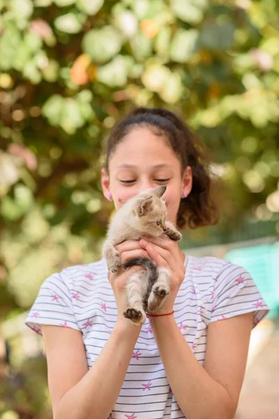 Un bambino felice tiene un gatto tra le braccia. Ragazza catturato un piccolo gattino. — Foto Stock