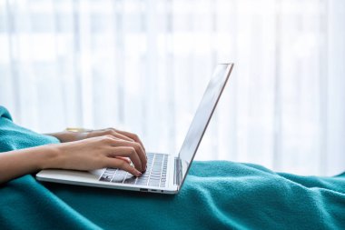Yatakta dizüstü bilgisayarla çalışmak hastane arka planında, hastalık zamanında iş yapma kavramı.